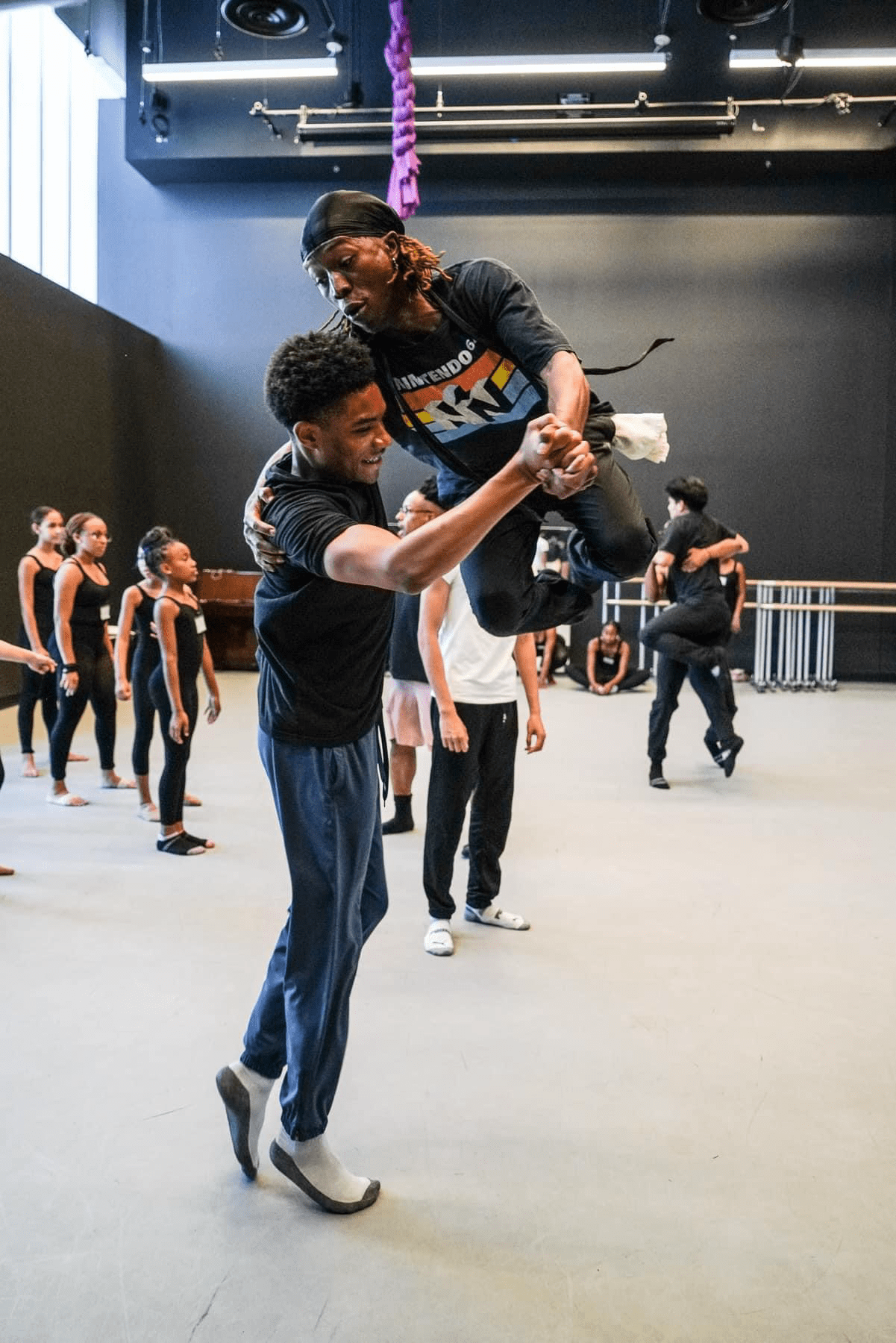 A male ballroom dancer on the left tossing a student into the air. 