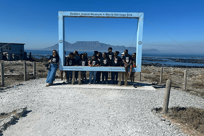 2025 trip cohort posing for group photo outside Robben Island Prison