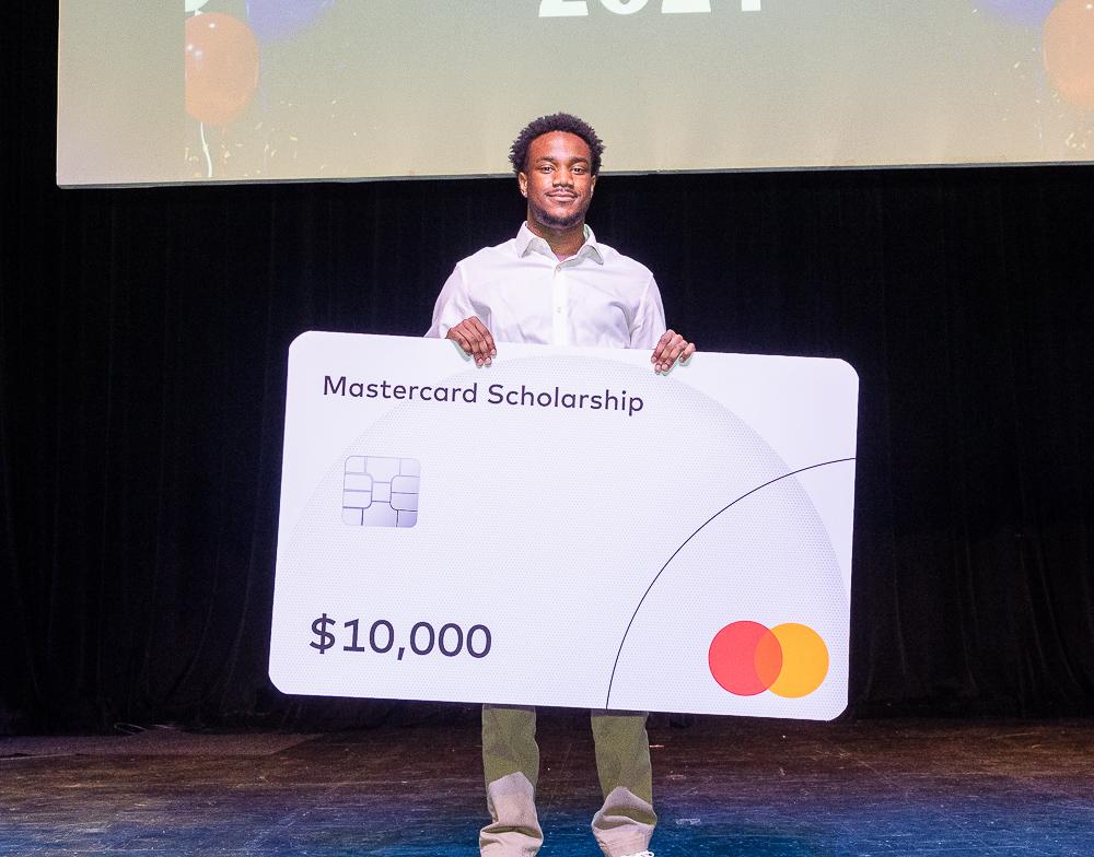 Joshua Taylor holds a large fake MasterCard credit card