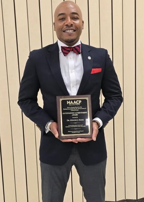 Kyrone Davis holding NAACP award plaque