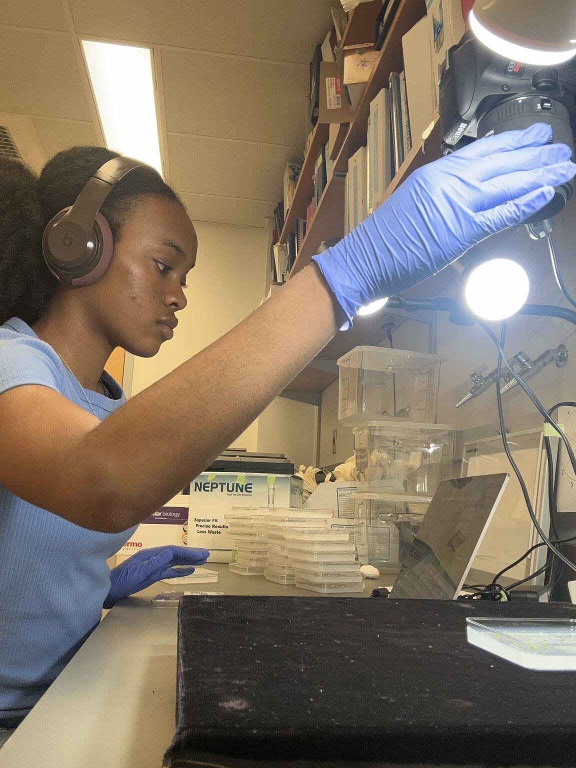 Camille Wimberly in a lab conducting research. she is wearing purple latex gloves