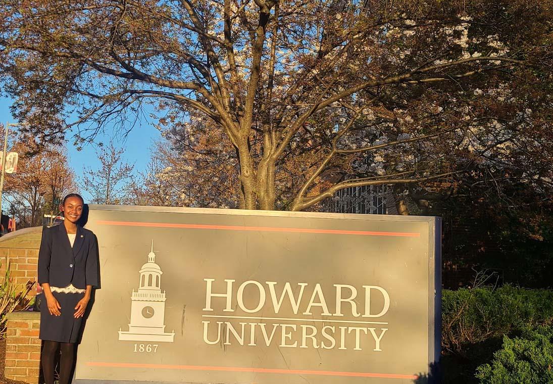 Camille Wimberly standing left of the Howard University sign outside