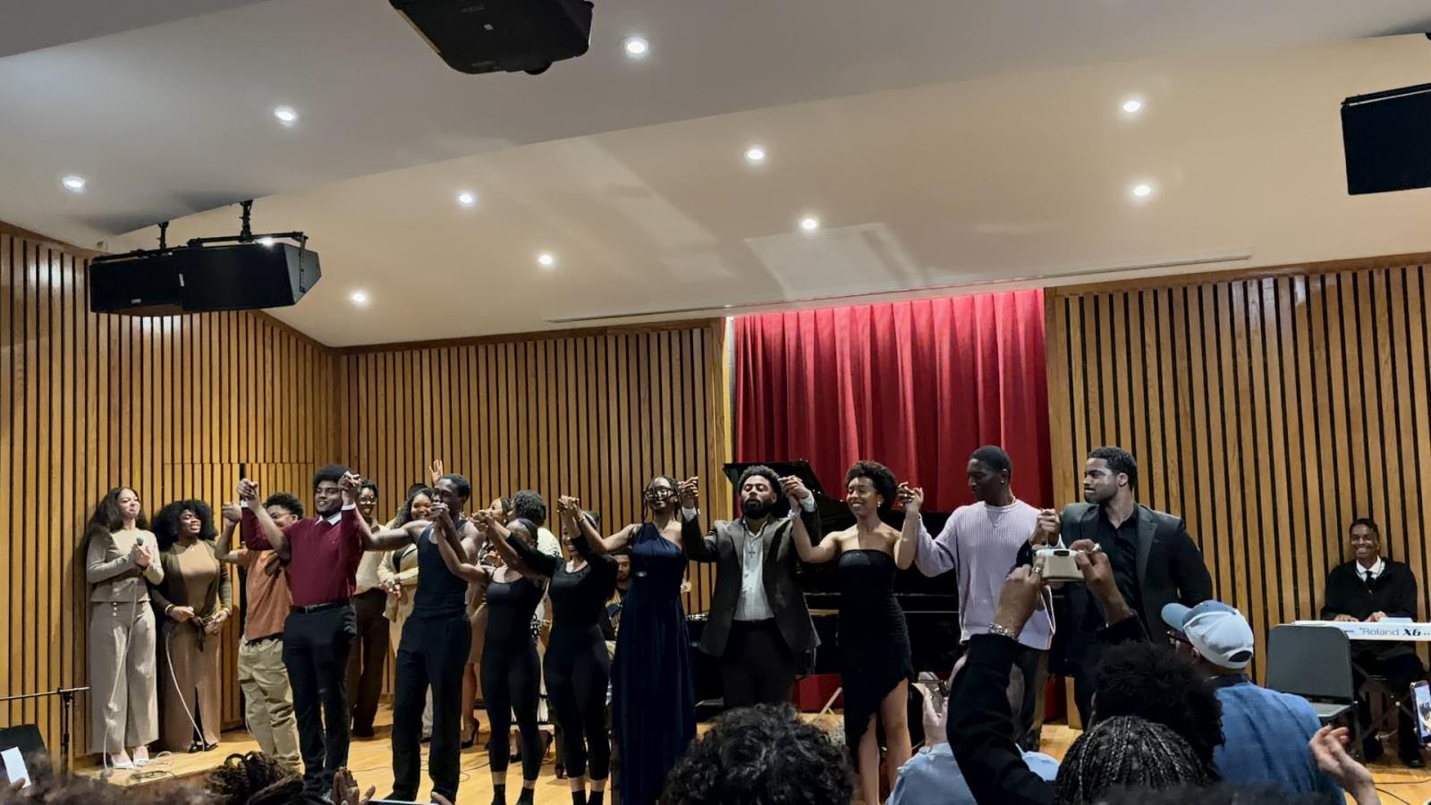 Dillon Debourg and several other musicians holding hands in the act of taking a bow