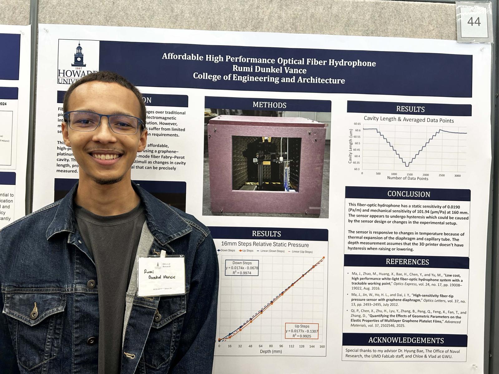 A male college student standing in front of a poster board that has research findings on it