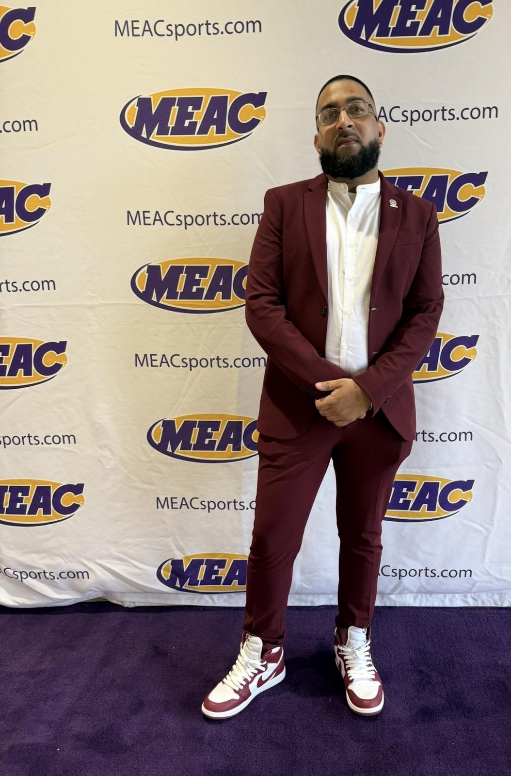 Bilal Badruddin standing in front of a backdrop that says MEAC multiple times across it