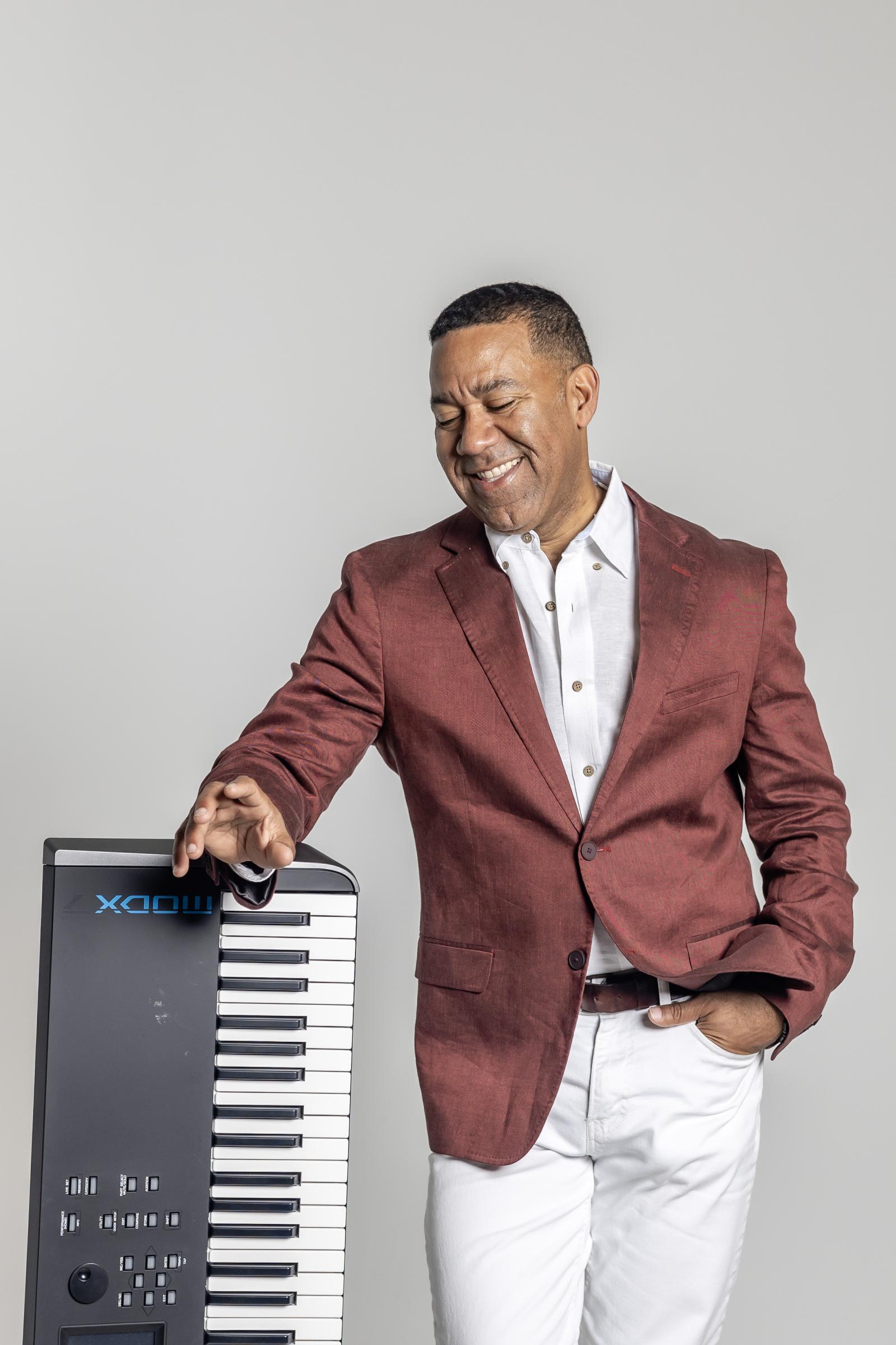 Marcus Johnson standing with his hand on a sideways keyboard on his left