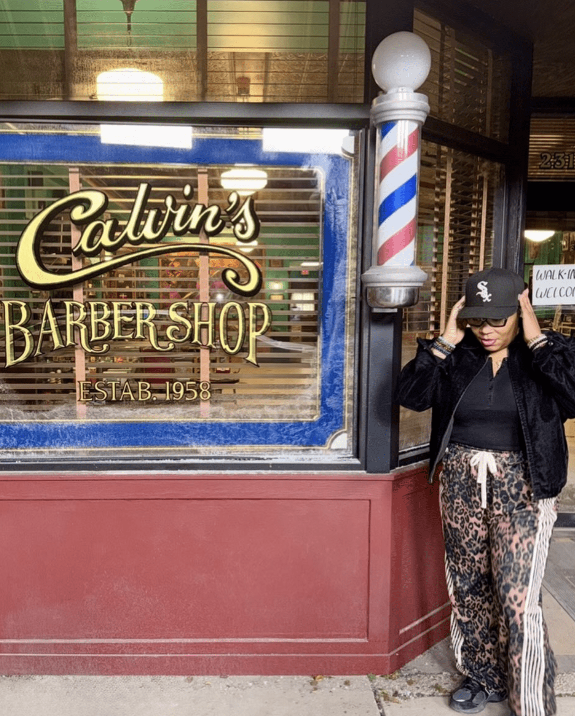 Marci Rodgers on the set of the Barbershop tv series. She's standing next to a sign that says Calvin's Barbershop 