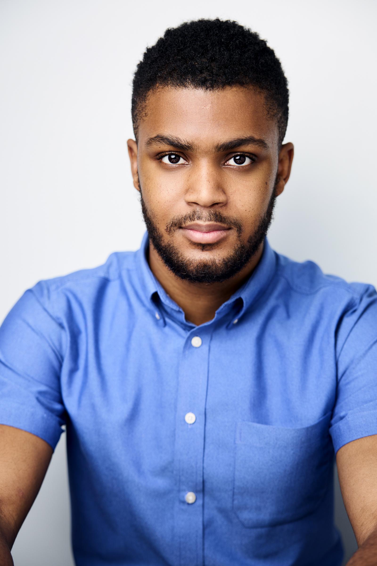 Howard alum Trenton McKenzie Beavers headshot. He's in a blue collared button up shirt