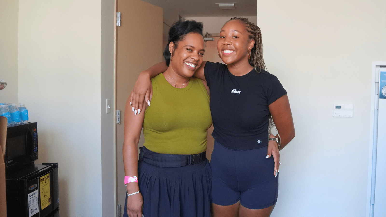 A mother and daughter smiling and standing side by side as they pose for the photo in a residence Hall at Howard University