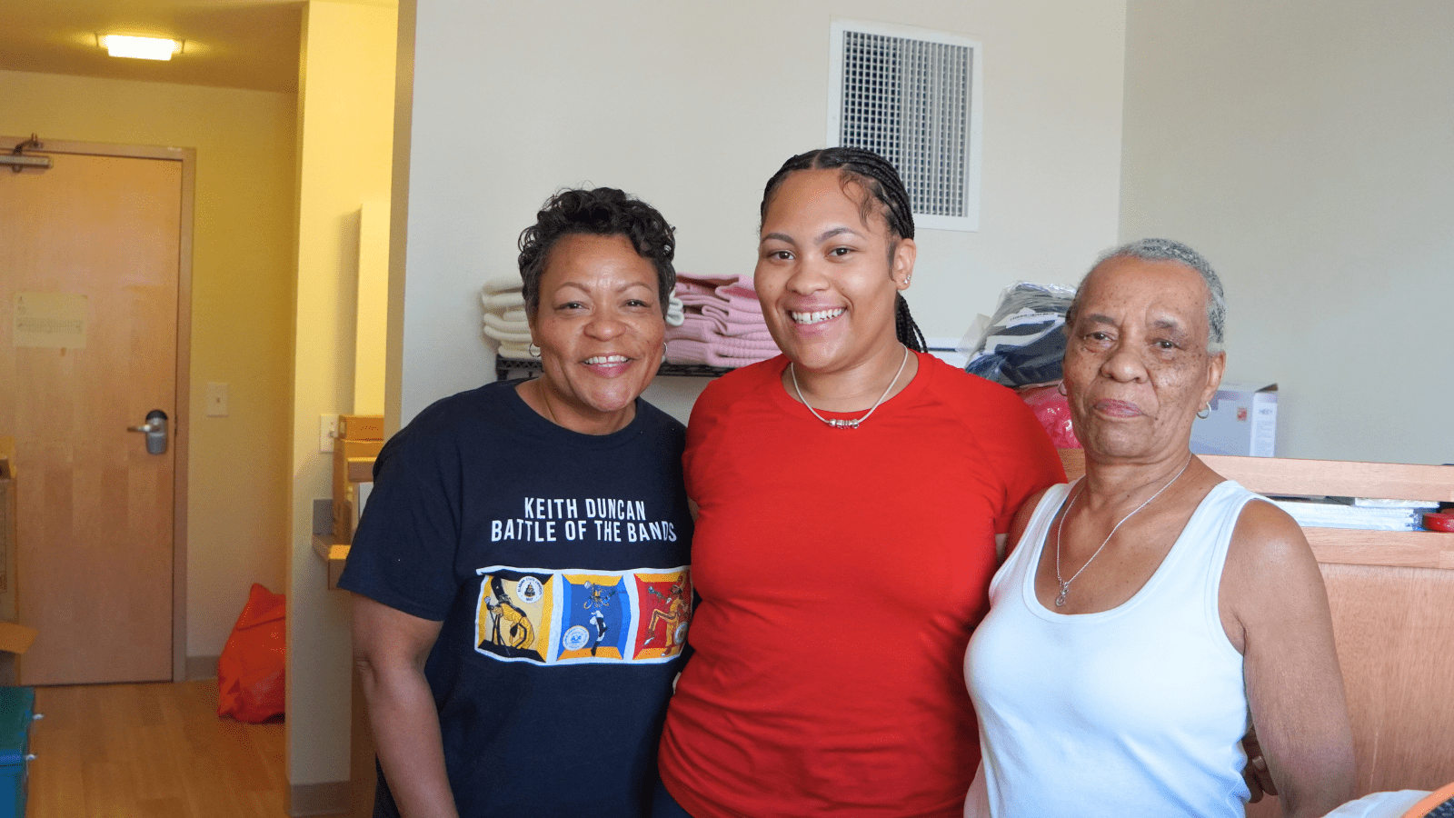 Three generations of women smiling at the camera in a residence hall at Howard University