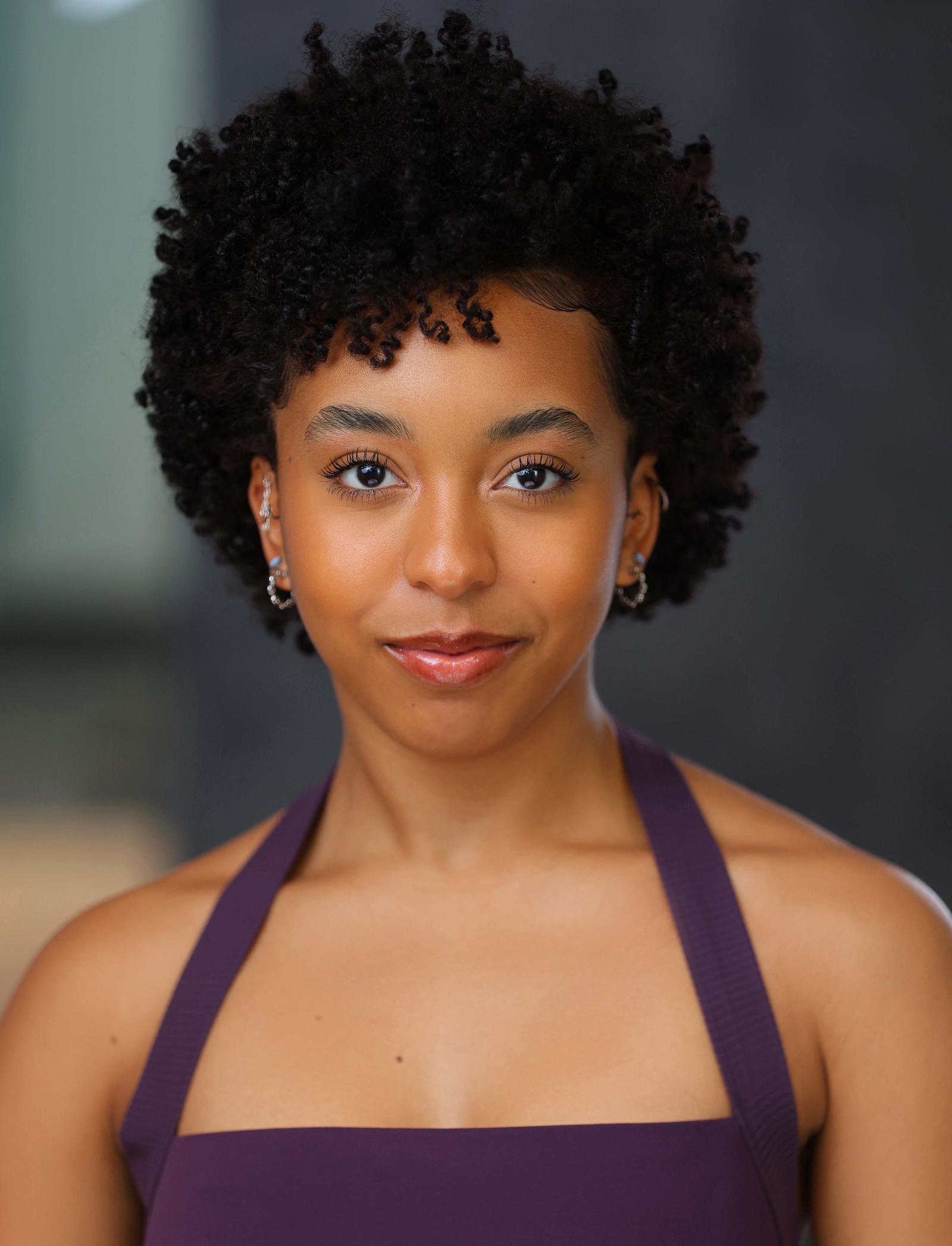 Howard alum Mikari Tarpley in a headshot. She's wearing an auburn top that has thin straps