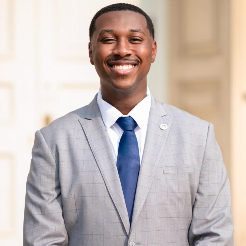 Jeremy Allman smiling wearing a gray suit and a blue tie