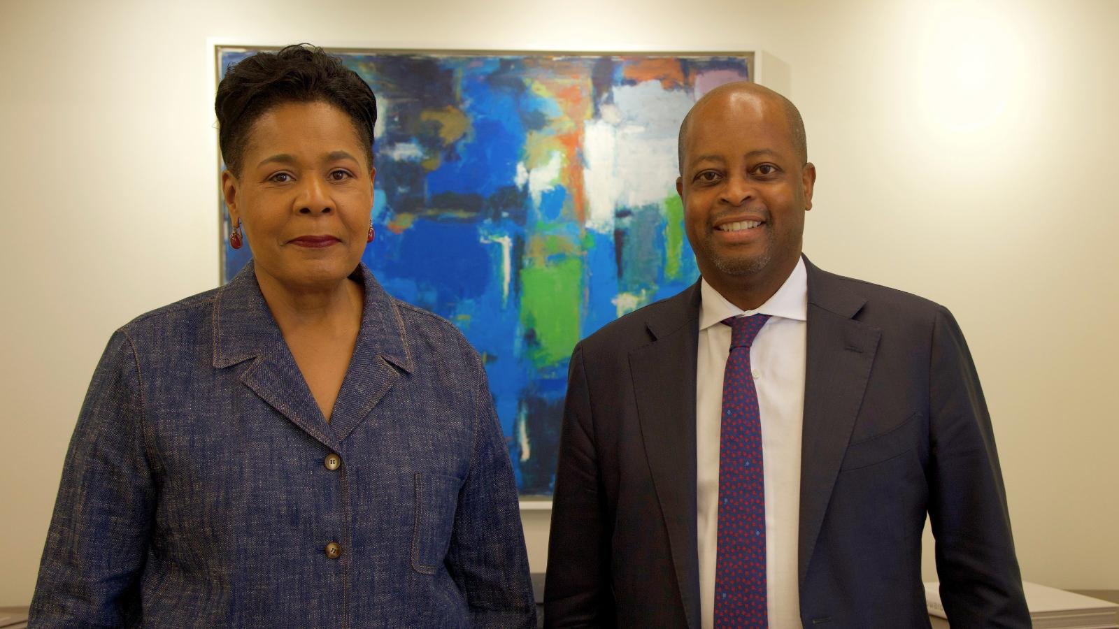 A woman and a man posing for a photo. The man on the right is smiling.