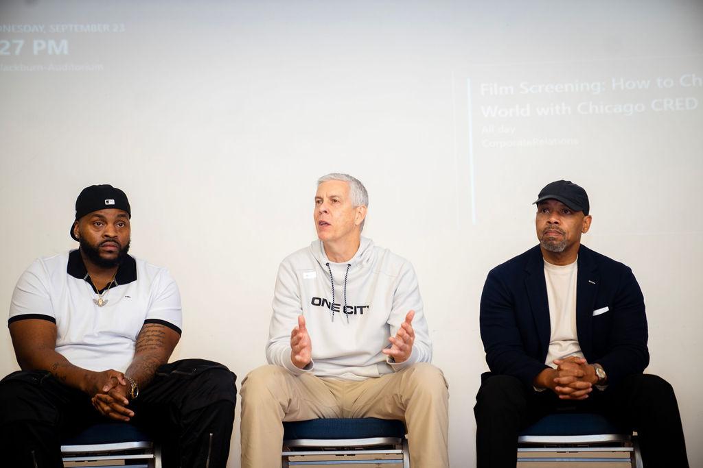 Panel with three men seated side by side at Blackburn Digital Auditorium for screening of "How to Change the World" 