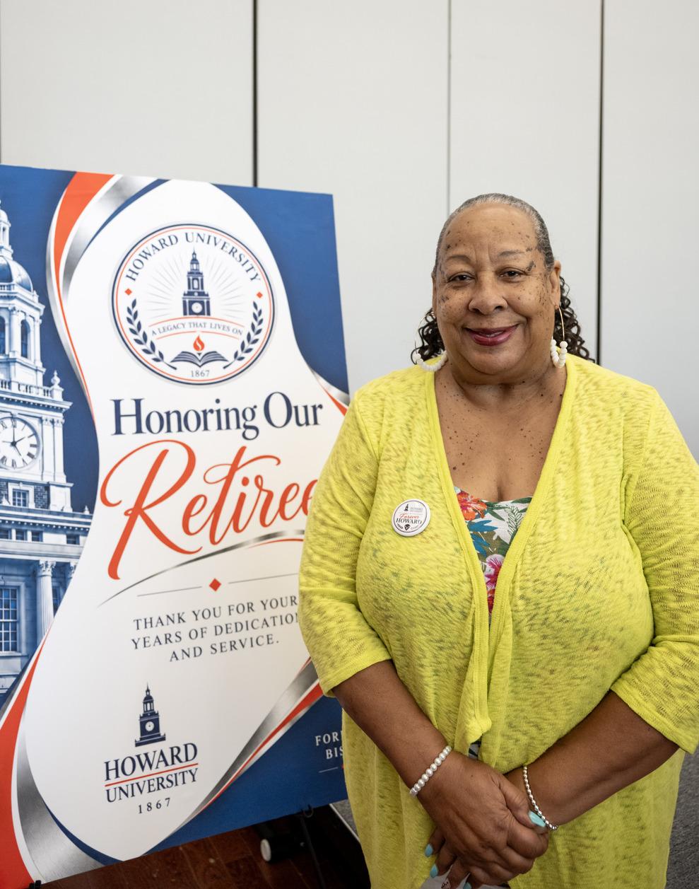 Deborah Boatman at Retirement Celebration wearing a yellow top standing in front of an event poster
