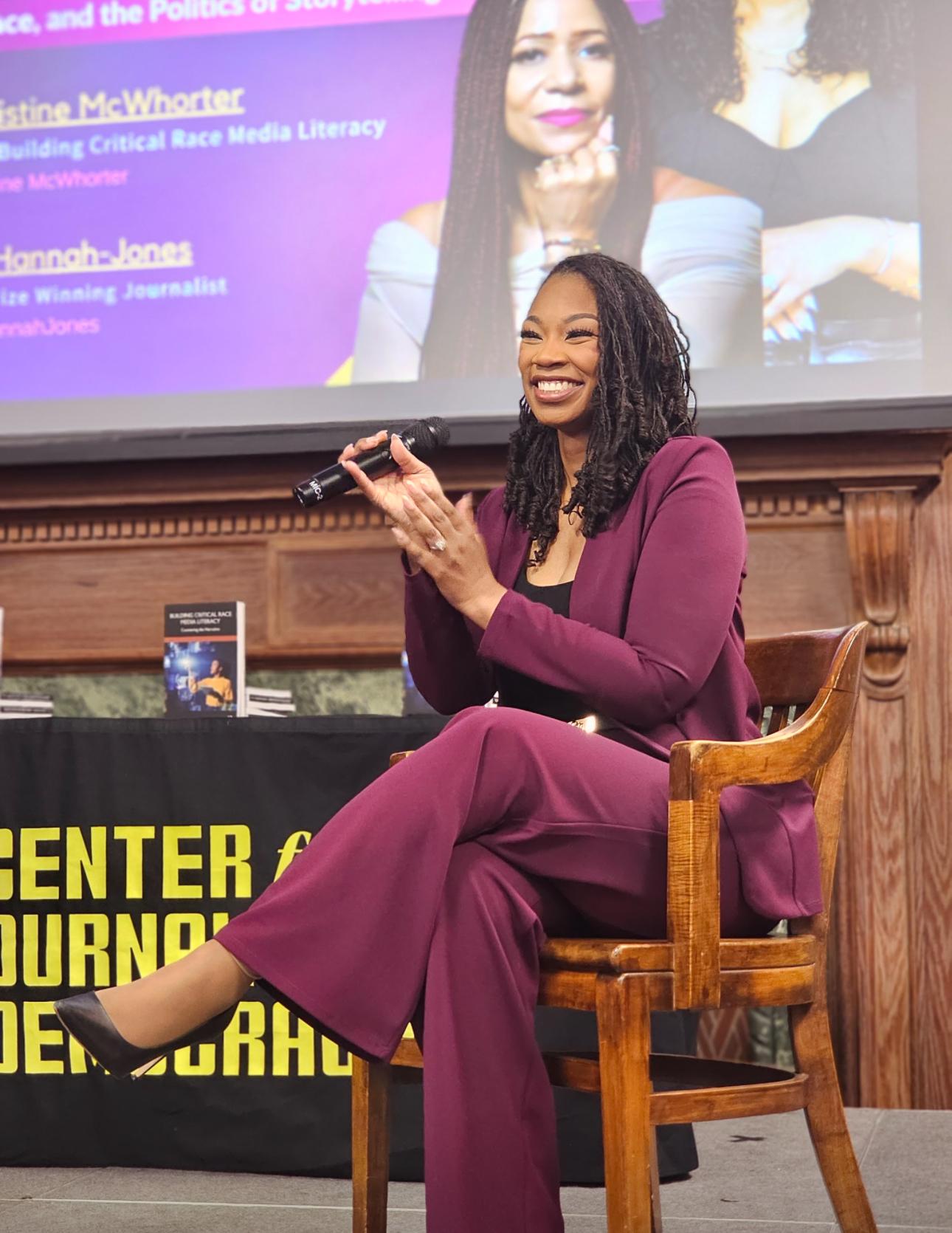Howard associate professor Christine McWhorter sitting in a chair wearing a purple suit at her book release event on Howard's campus
