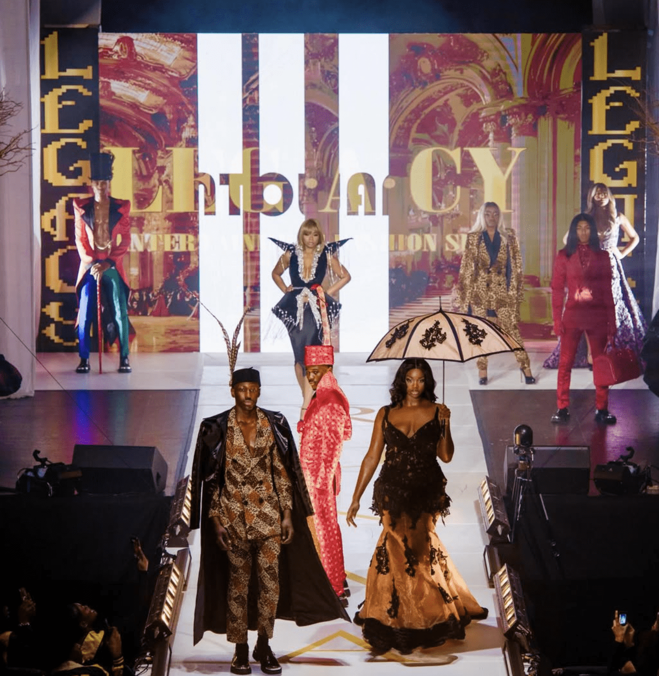 Models Inc. fashion show with several models walking the runway in very colorful outfits