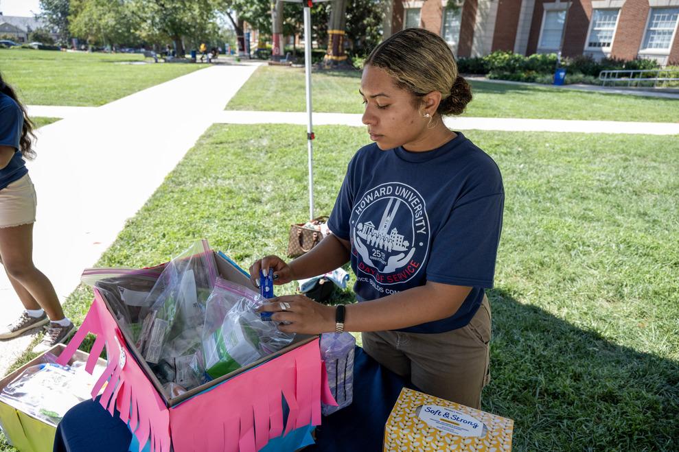 Howard student wearing a blue Student Veterans of America shirt while standing in The Yard under a tent