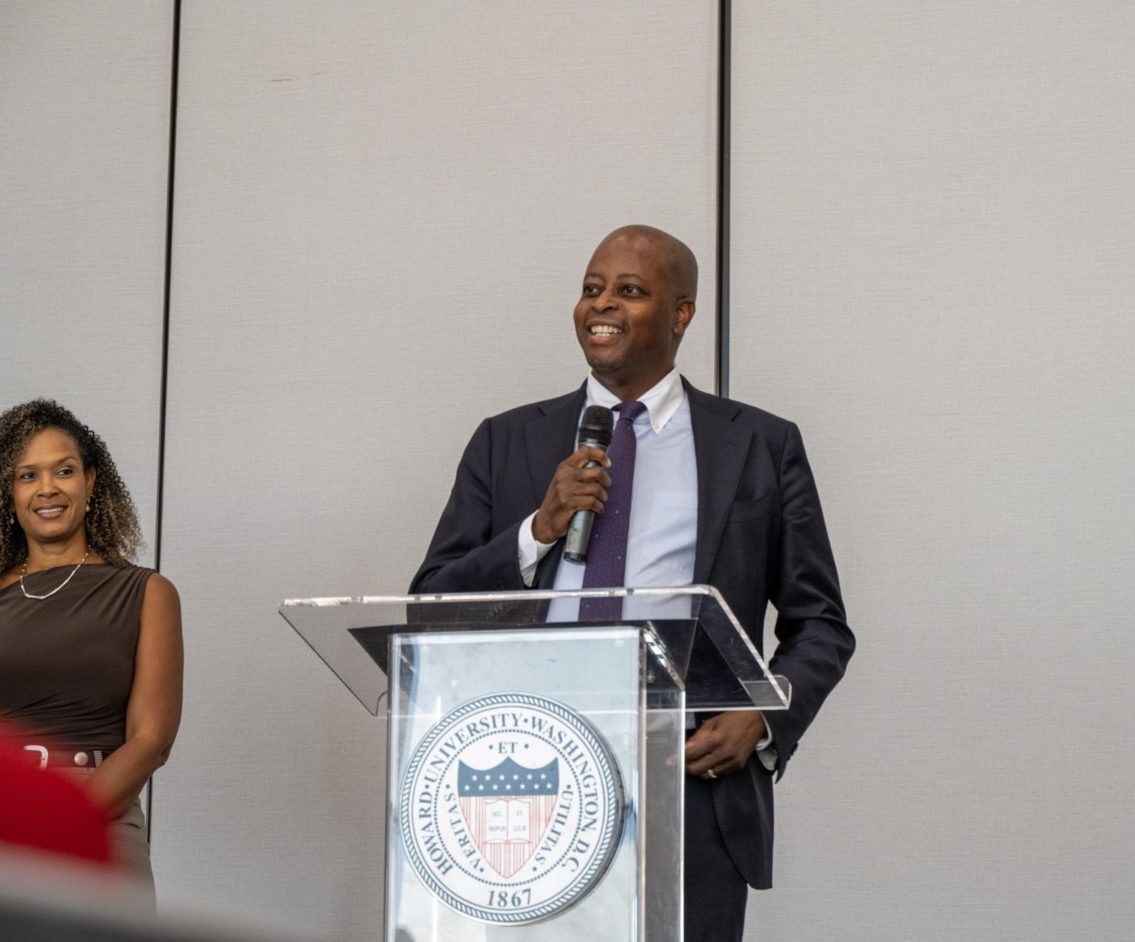 Dr. Wayne A.I. Frederick wearing a dark suit talking at a podium in the Blackburn Center Ballroom